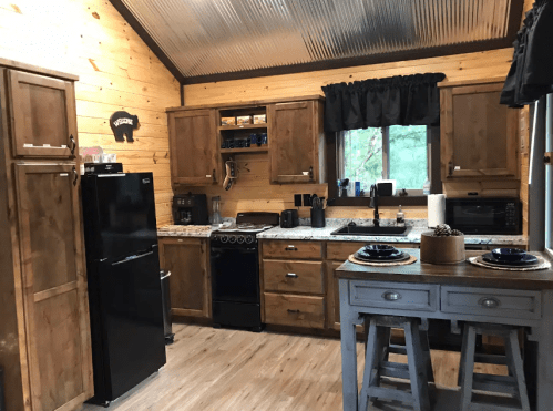 Cozy kitchen with wooden cabinets, granite countertops, and modern appliances, featuring a rustic design and natural light.