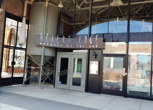 Entrance to Desert Edge Brewery at the Pub, featuring large glass doors and a prominent sign.