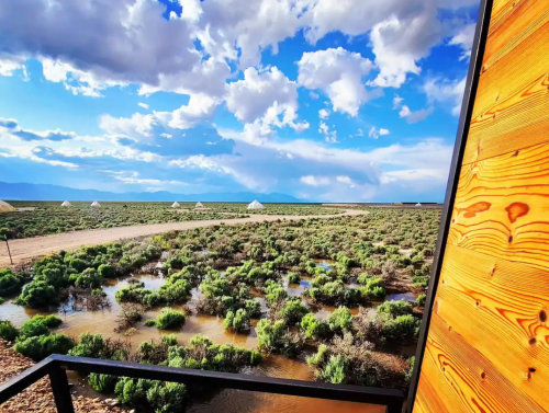 A scenic view of a green landscape with clouds and mountains in the background, framed by a wooden structure.