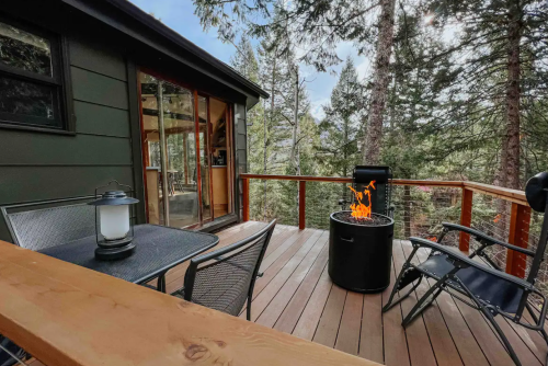 Cozy deck with a fire pit, surrounded by trees, featuring a table and chairs for outdoor relaxation.