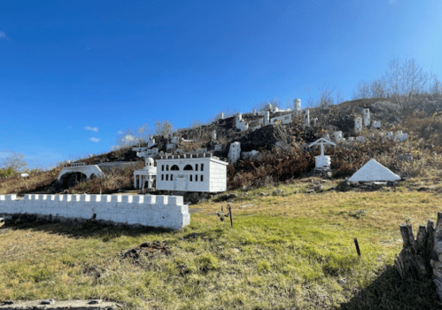 A hillside covered with miniature white buildings and structures against a clear blue sky.