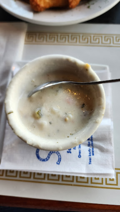 A small bowl of creamy soup with a spoon, placed on a napkin at a restaurant table.