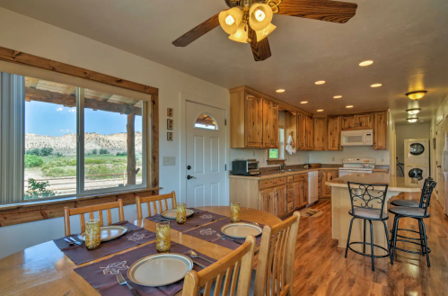 Bright kitchen with wooden cabinets, dining table set for four, and scenic views through large windows.