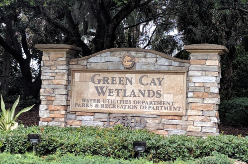 Sign for Green Cay Wetlands, featuring stone design and information about water utilities and parks department.
