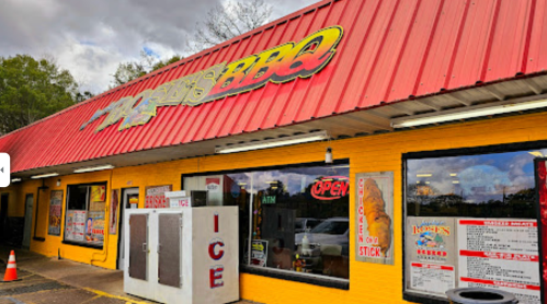 A colorful BBQ restaurant with a red roof, open sign, and ice vending machine outside.