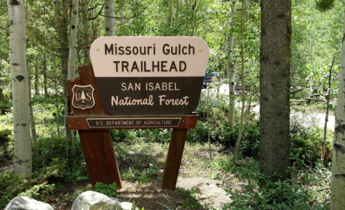 Sign for Missouri Gulch Trailhead in San Isabel National Forest, surrounded by trees and greenery.