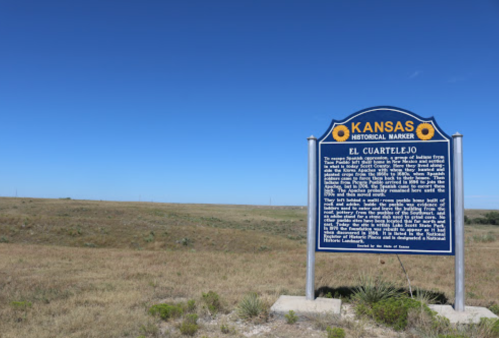 A historical marker for El Cuarteljo in Kansas, set against a clear blue sky and open grassland.