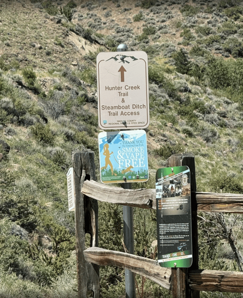 Signpost indicating access to Hunter Creek Trail and Steamboat Ditch Trail, with a no smoking and vaping message.