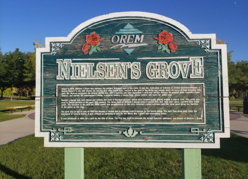 Sign for Nielsen's Grove in Orem, featuring decorative roses and information about the park's history and features.