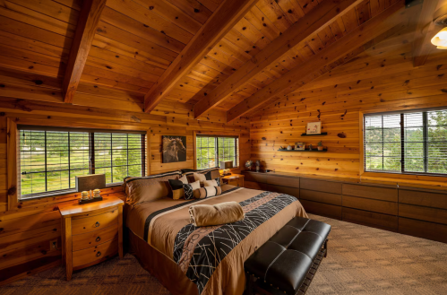Cozy wooden bedroom with a large bed, natural light, and rustic decor, featuring a warm, inviting atmosphere.