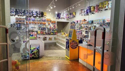 A colorful toy store filled with plush toys, games, and various merchandise, featuring bright displays and shelves.