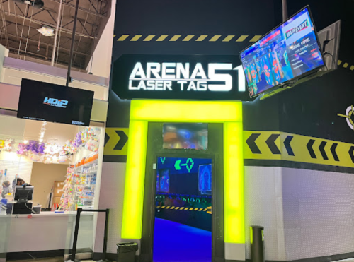Entrance to Arena Laser Tag 51, featuring bright neon lights and screens displaying game information.
