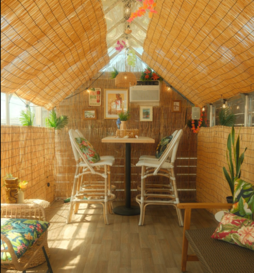 Cozy indoor space with bamboo decor, tropical plants, and a small table with chairs, creating a warm, inviting atmosphere.