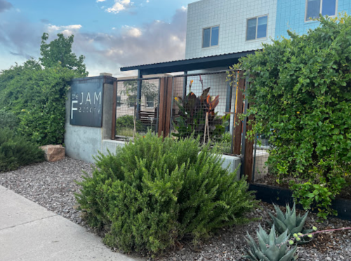 Exterior view of The Jam Factory, featuring greenery and a modern building with a sign.