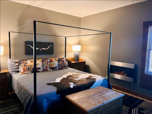 Cozy bedroom with a four-poster bed, decorative pillows, a fireplace, and warm lighting.