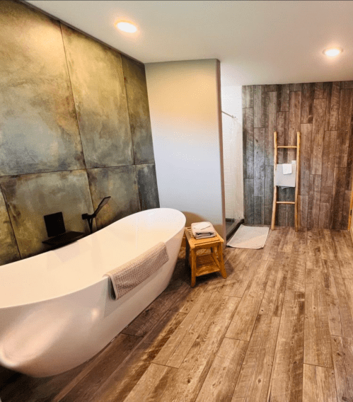 A modern bathroom featuring a freestanding tub, wooden accents, and a textured wall design.