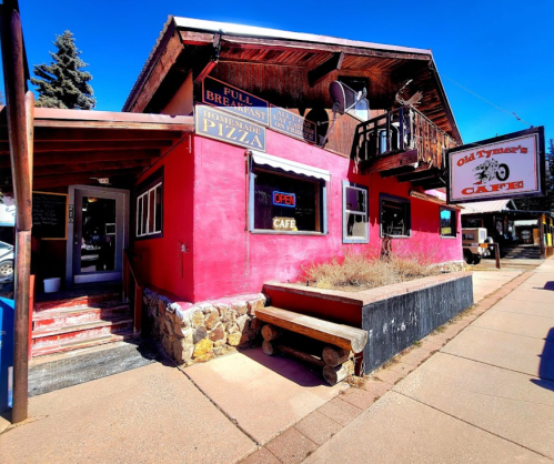 A colorful café with a sign reading "Open," featuring a rustic exterior and outdoor seating.