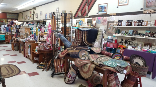 A cozy shop interior filled with various handmade crafts, rugs, and decorative items on display.