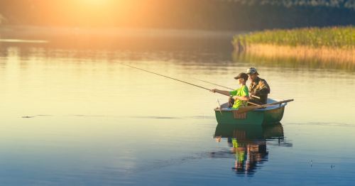 Two people sitting in a small boat on a lake fishing in West Virginia during sunset
