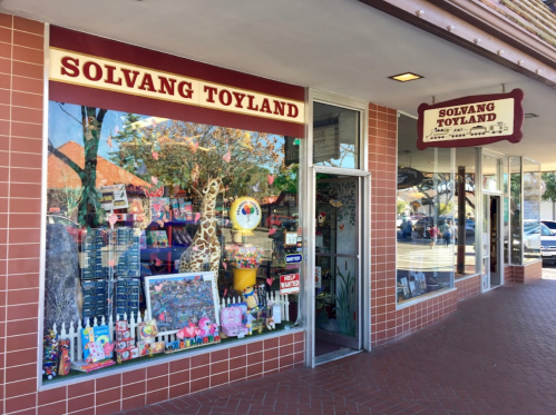 A colorful toy store window display featuring various toys and decorations in Solvang, California.