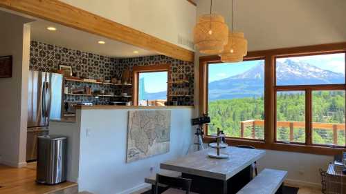 Bright, modern interior with a dining area, large windows showcasing a mountain view, and stylish pendant lights.