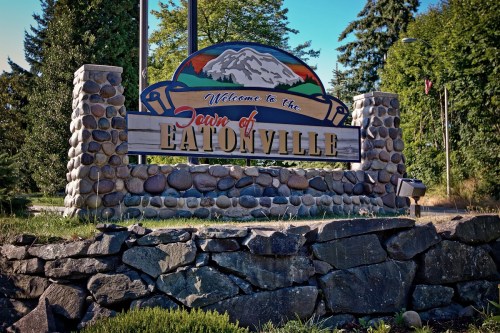 Welcome sign for the town of Eatonville, featuring a mountain backdrop and stone pillars.