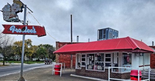 A retro ice cream shop with a red roof and a vintage sign, set against a cloudy sky.