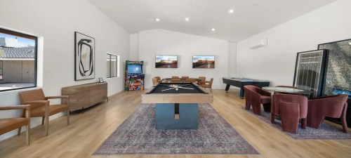 A spacious game room featuring a pool table, arcade machine, dining area, and modern decor.