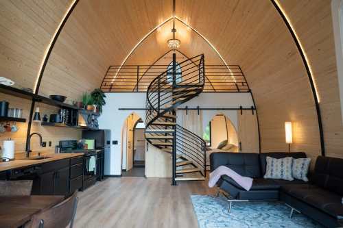 Modern interior of a cozy, wooden home featuring a spiral staircase, open living space, and stylish furnishings.