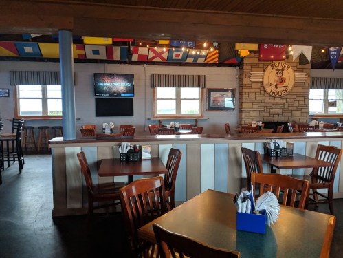 Interior of a restaurant with wooden tables and chairs, nautical decor, and colorful flags hanging from the ceiling.