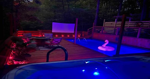 A serene outdoor space at night featuring a pool, lounge area, and illuminated decorations amidst trees.