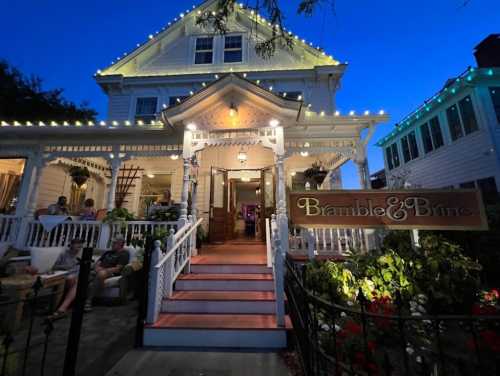 A charming restaurant, Bramble & Brine, with outdoor seating, illuminated by string lights at dusk.