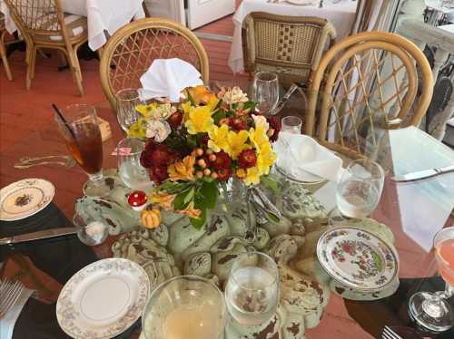 A dining table set with floral centerpiece, glassware, and elegant plates in a bright restaurant setting.