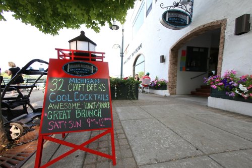 A sign outside a restaurant advertises Michigan craft beers, cocktails, lunch, and brunch hours on weekends.