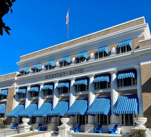 Historic building with blue and white striped awnings, labeled "Buckstaff Baths," under a clear blue sky.