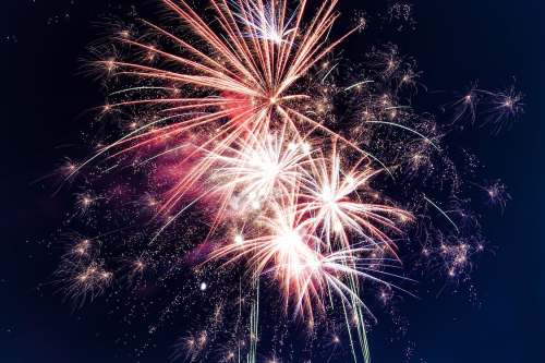 Colorful fireworks explode in the night sky, creating a vibrant display of light and sparks.