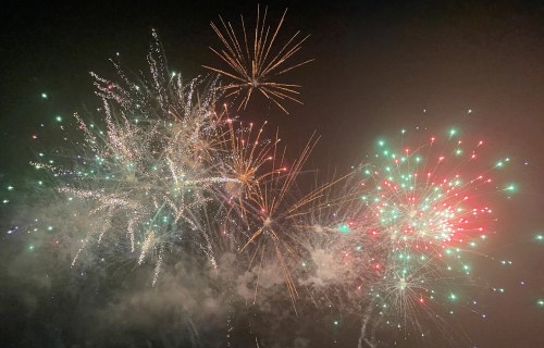 Colorful fireworks burst in the night sky, creating a vibrant display of lights and patterns against a dark background.