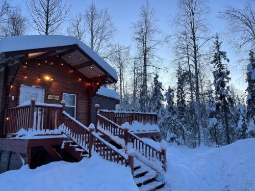 snowy cabin with stairs and lights in alaska