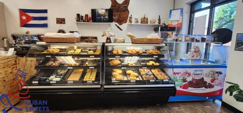 A display case filled with various Cuban pastries and sweets in a cozy bakery setting.