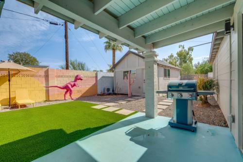 A backyard with artificial grass, a grill, and colorful dinosaur murals on the walls.