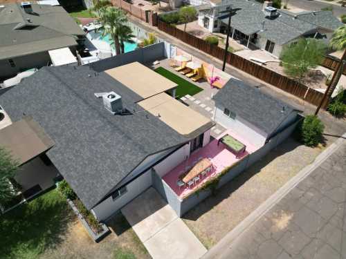 Aerial view of a residential backyard with a pool, patio, and colorful lounge chairs surrounded by fences and landscaping.