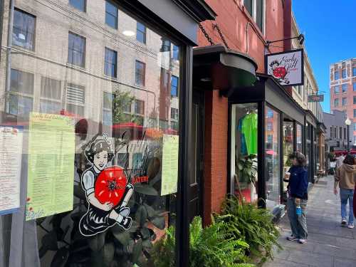 A storefront with a vintage logo of a girl holding a tomato, featuring menus and a sign for "Early Girl Eatery."