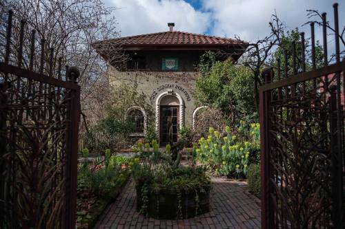 A charming building surrounded by lush greenery and a decorative gate, under a partly cloudy sky.
