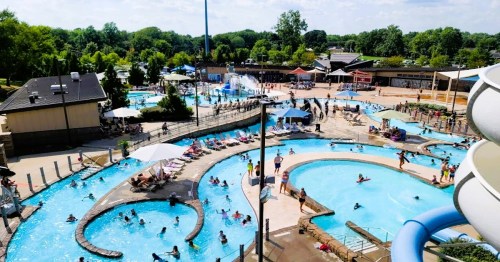 Aerial view of a busy water park with pools, slides, and people enjoying the sunny day.