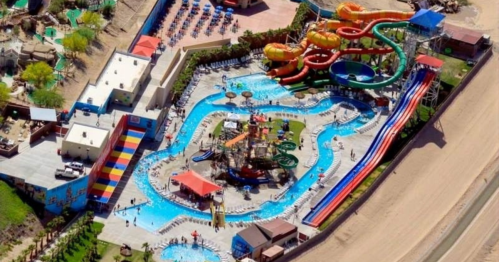 Aerial view of a vibrant water park featuring slides, pools, and lounging areas surrounded by greenery.