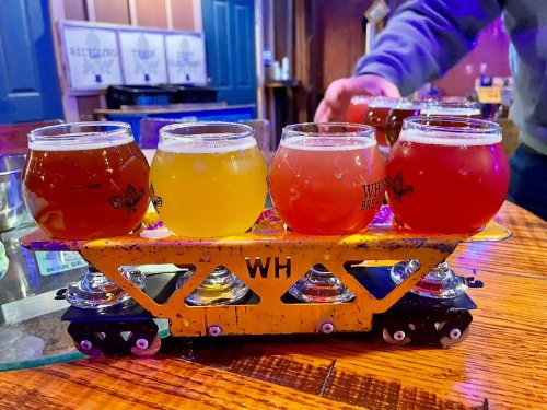 A colorful flight of craft beers served on a miniature train, showcasing various styles in small glasses.
