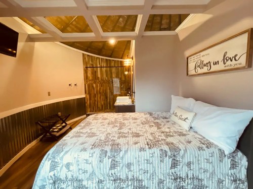 Cozy bedroom with a patterned bedspread, wooden accents, and a rustic decor style, featuring a curved wall and a TV.