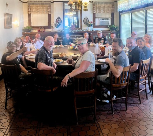 A large group of people gathered around a round table in a cozy dining room, enjoying a meal together.