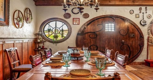 interior shot of hobbit home with large rustic dining table and circular door and window
