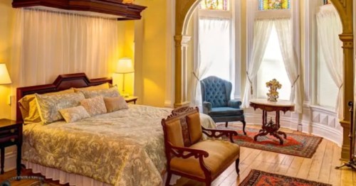 a luxurious room with a bed, chairs, and stained glass windows at Shakespeare Chateau Inn and Gardens Bed & Breakfast